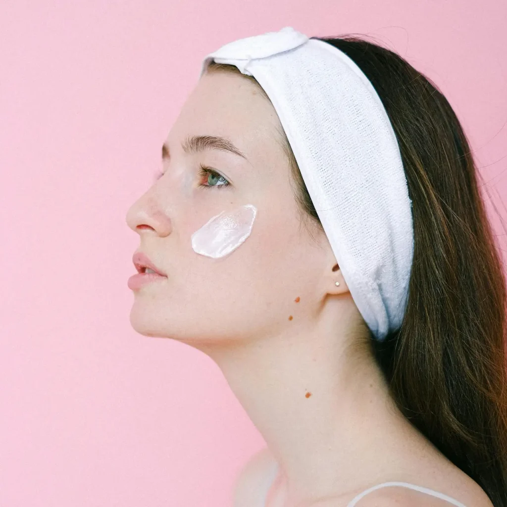 Zbliżenie na dłoń delikatnie wmasowującą bogaty krem nawilżający, ilustrujące znaczenie odpowiedniej pielęgnacji suchej skóry dla jej zdrowia i komfortu.