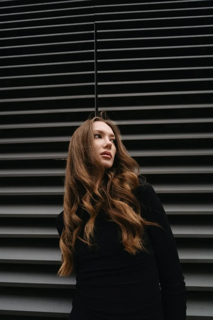 Młoda kobieta w modnej, warstwowej stylizacji miejskiej idzie ulicą w Krakowie, prezentując najnowsze trendy w street style.