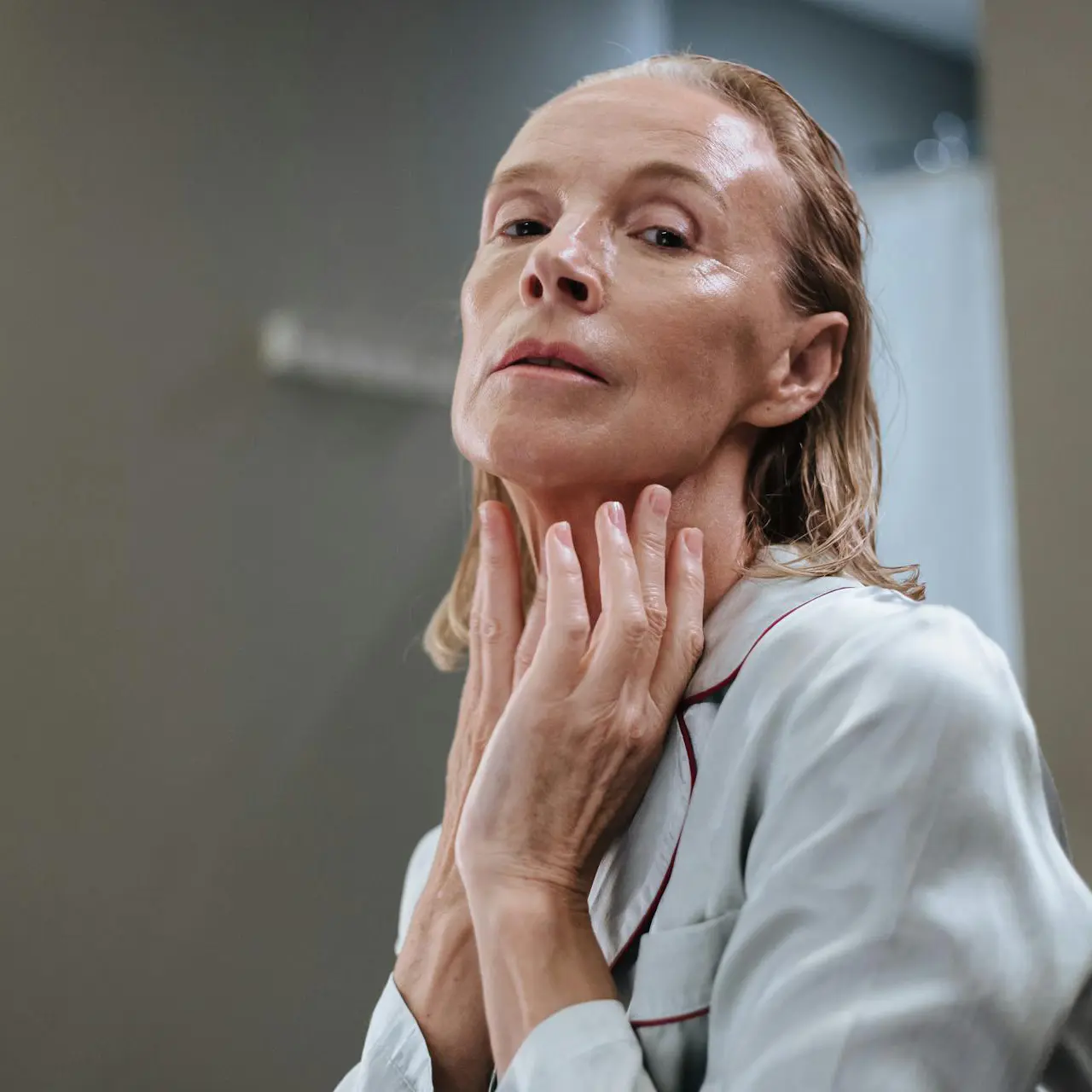 Zbliżenie na eleganckie butelki i słoiczki zawierające skuteczne kosmetyki anti-aging, ułożone na marmurowej powierzchni. Wskazują na jakość i luksus.